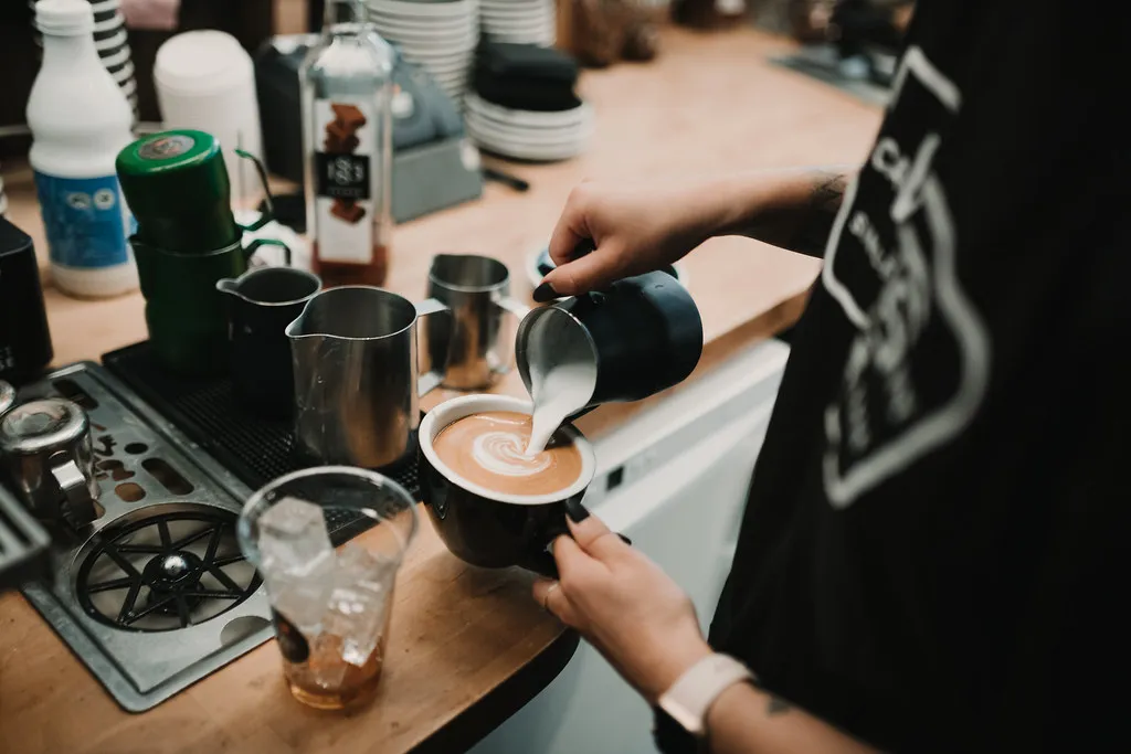 A barista finishing a coffee at the pass
